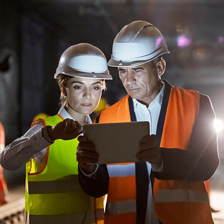 female and male with hardhats looking at tablet